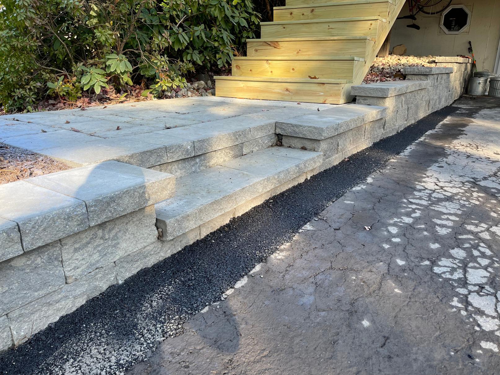 Photos of steps leading up to the front door of a house, a long driveway that has been seal-coated, and a retaining wall 